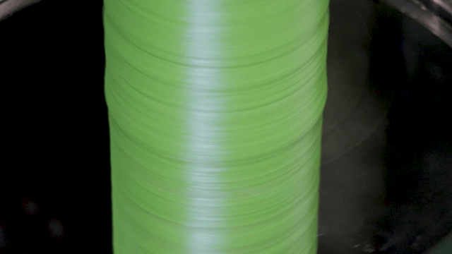 Green threads rapidly coiling on machine
