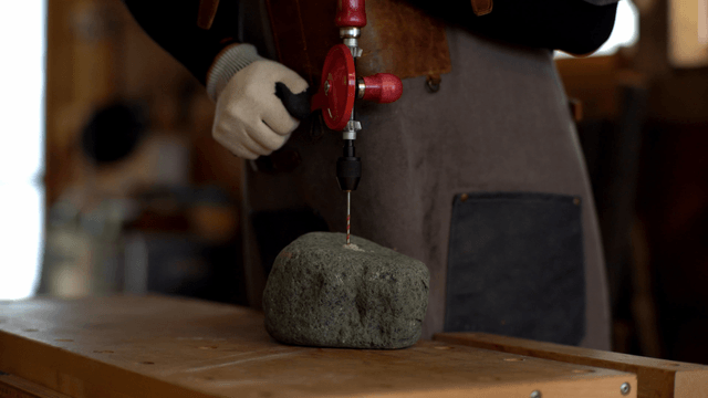 Person drilling a stone with a hand drill