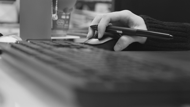 Hand holding a pen on a computer mouse