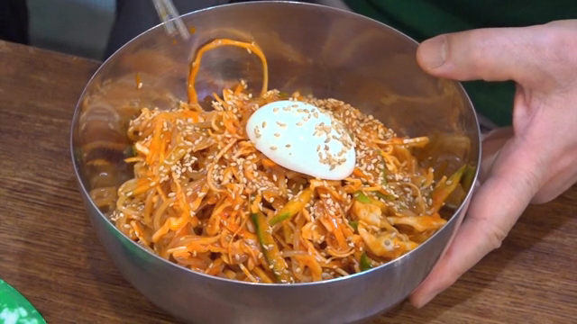 Egg on top of spicy chewy noodles with lots of vegetables