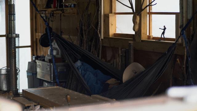 Person resting on a hammock in a woodcraft workshop