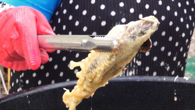 Fried fish being lifted from hot oil