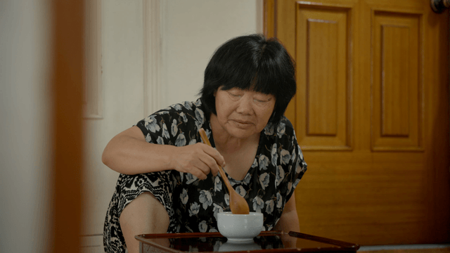 An elderly woman eating alone indoors