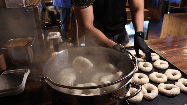 Bagels placed into boiling water in a pot