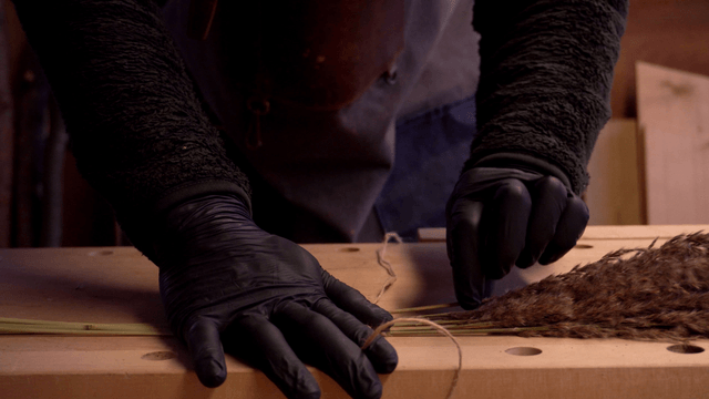 Person crafting with dried plants indoors