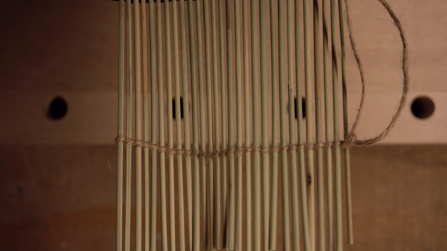 Hand arranging dried reeds on a table