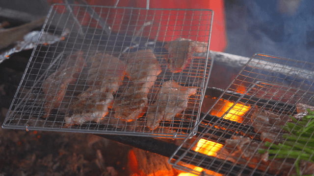 Pork belly and vegetables grilling over charcoal fire