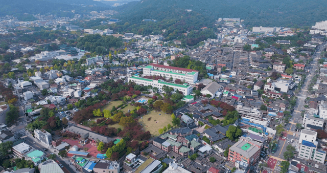 숲 배경의 한옥 마을과 현대 주택가 풍경