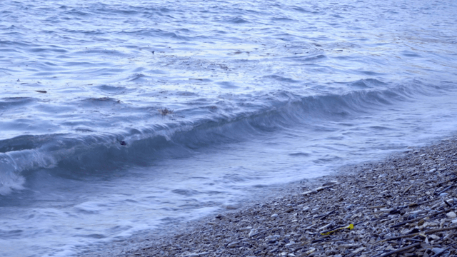 자갈 해변에 부딪히는 잔잔한 파도