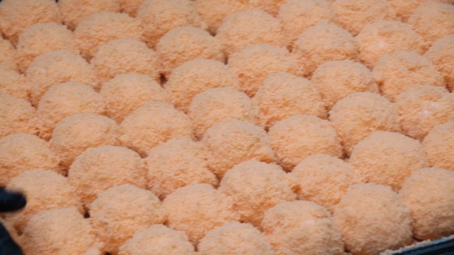 Pink rice cake being prepared on a tray