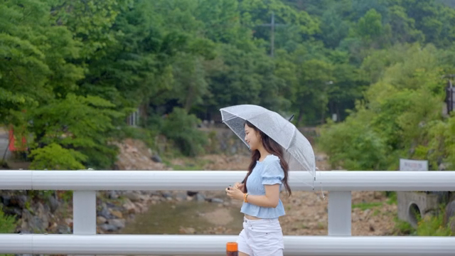 비 오는 날 우산을 쓰고 걷는 여성