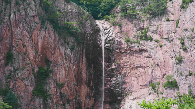 Small waterfall falling on rocky cliff