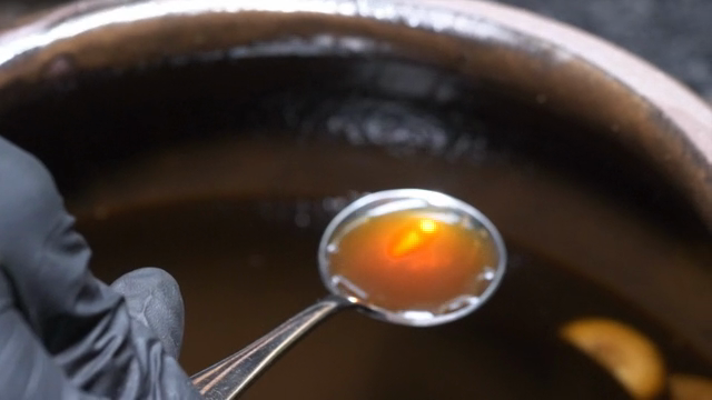 A spoon scooping soy sauce from a pot