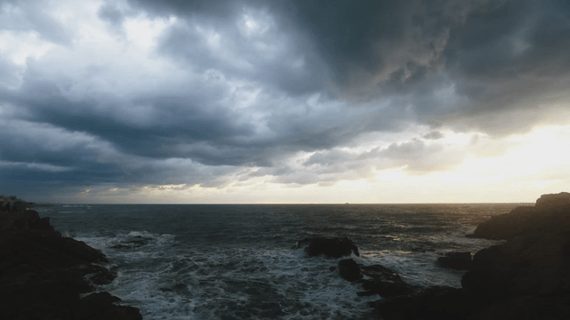 Sunrise over waves crashing on rocky coast