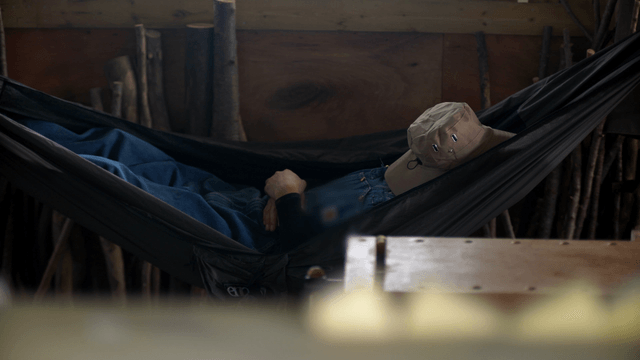 Person resting in a hammock inside a woodcraft workshop