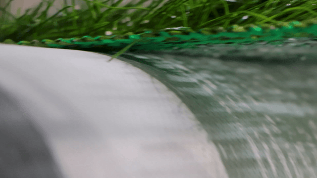 Artificial turf being manufactured on machine