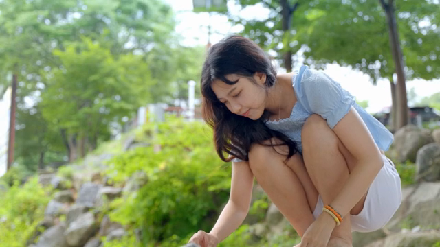 A woman crouching outdoors in a park