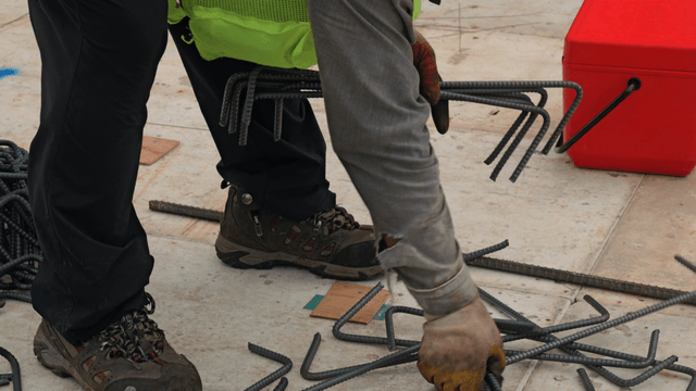 Worker handling steel rods on a construction site