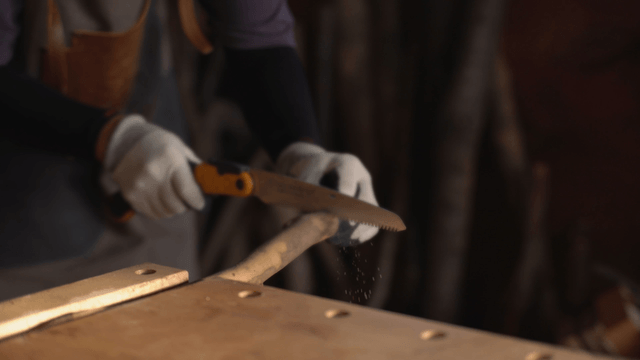 Person cutting wood with a saw