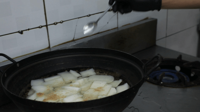 Chef adding seasoning to pot with radish