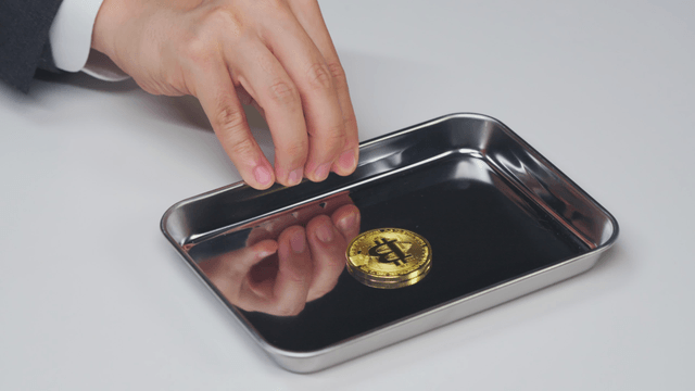 Hand offering a tray with a Bitcoin on it