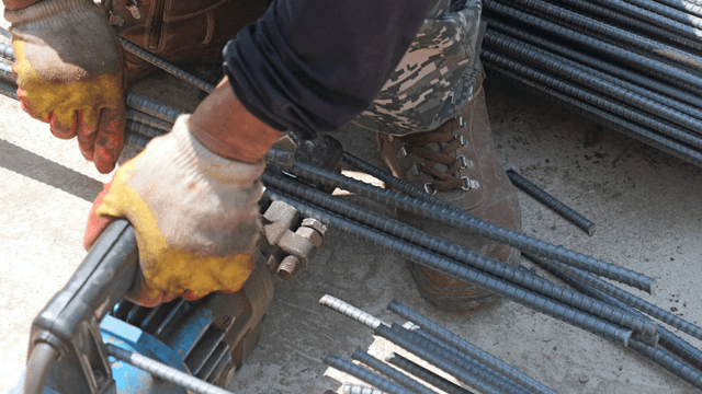 Worker cutting steel bars with a machine