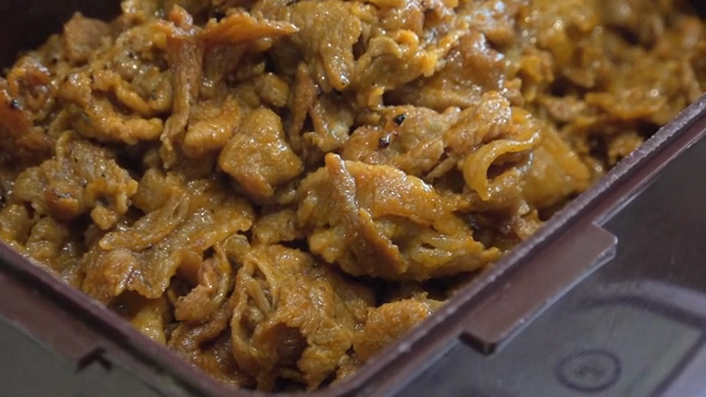 Marinated meat being mixed in a container