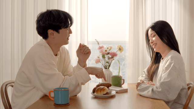 Happy couple talking over breakfast by window