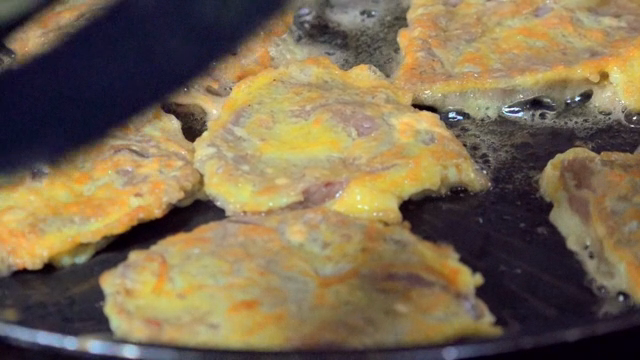 Pan-fried battered beef cooking in a pan
