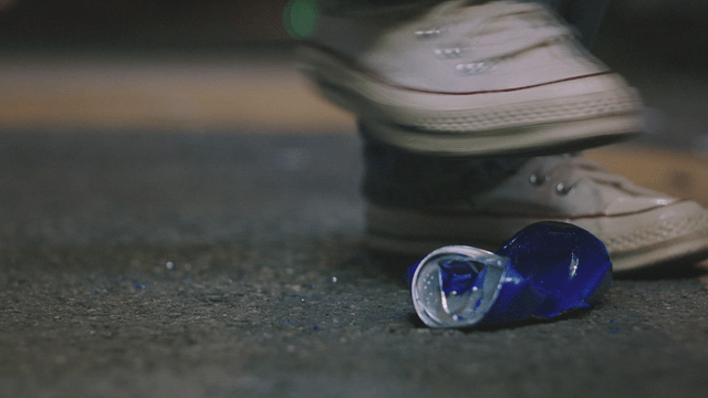 Person crushing a blue can on the street
