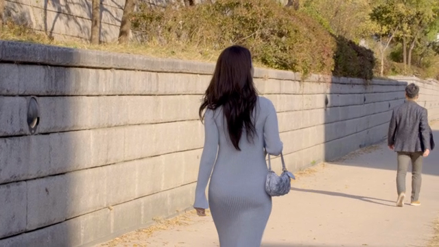 햇살이 비치는 길을 걷는 여성