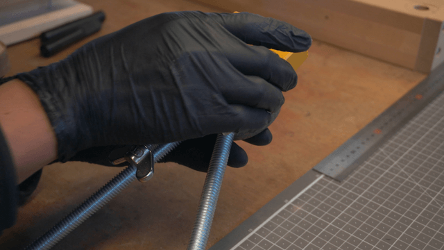 Hands assembling a metal bracket with a wooden block