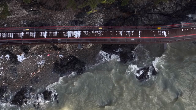 A bridge over rocky coastline with waves