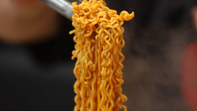 Tongs holding ramen from budaejjigae