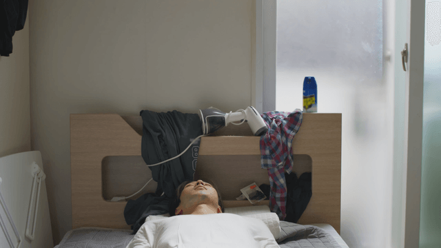 Man sleeping in a cluttered bedroom