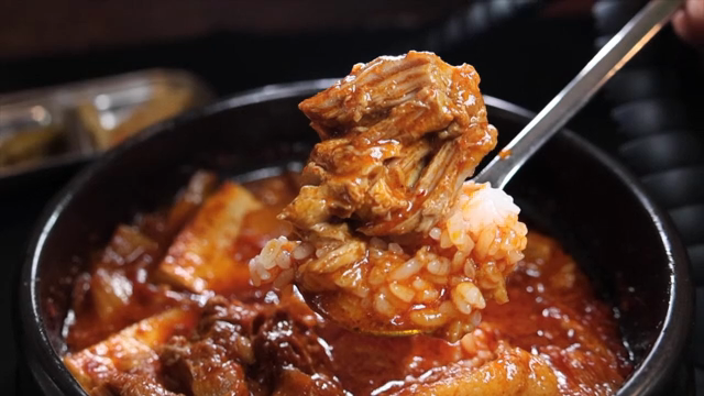 A spoonful of braised kimchipork placed on top of rice