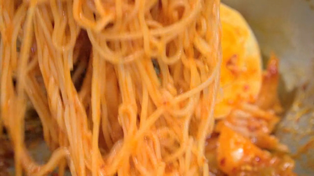 Spicy noodles being mixed in a bowl