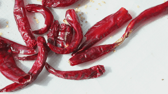 Dried red chili peppers on a white surface