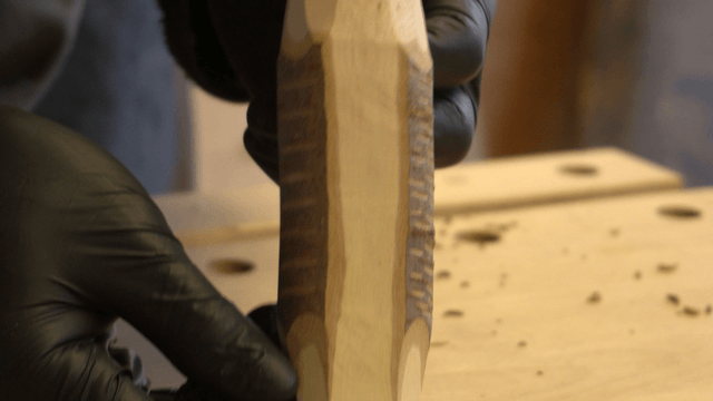 Hand inspecting a wooden piece in the workshop