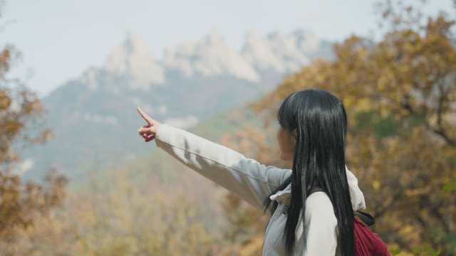 Smiling young woman pointing at autumn summit view