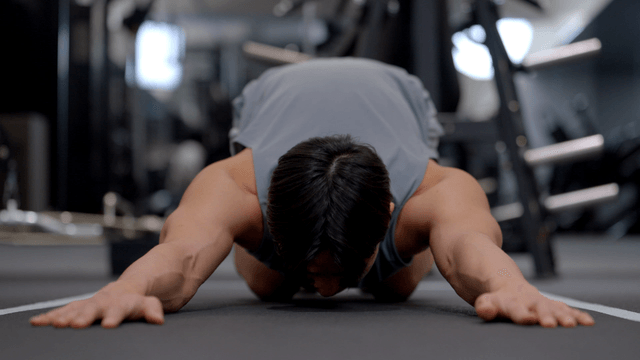 Young man stretching shoulders on gym floor