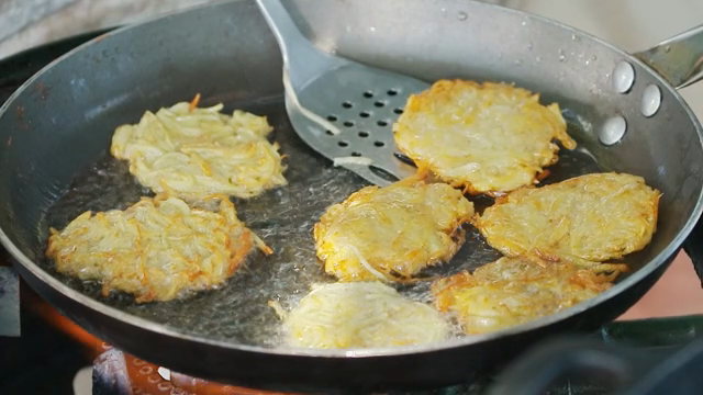 Golden potato pancakes frying in a pan