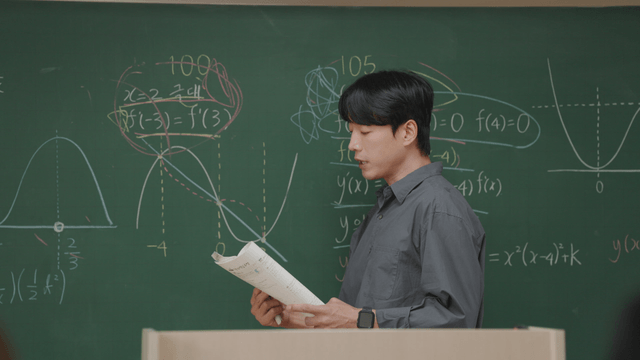 Teacher explaining math on a blackboard