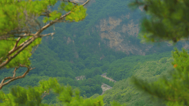 Blue mountain with steep cliff seen from afar