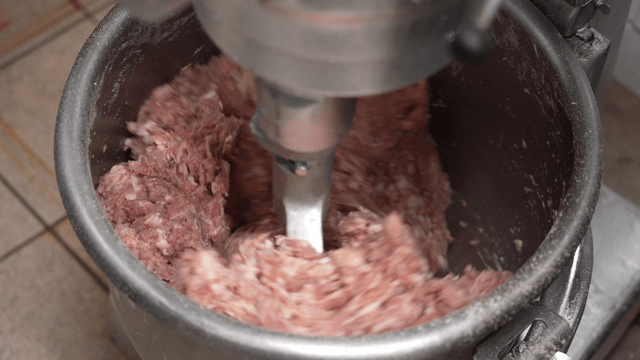 Meat being mixed in a large industrial mixer