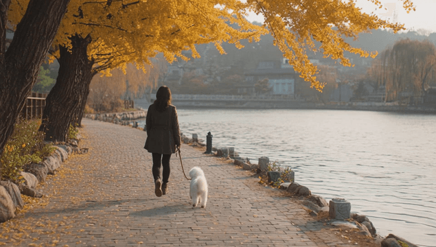 A woman walking a puppy along a lakeside path
