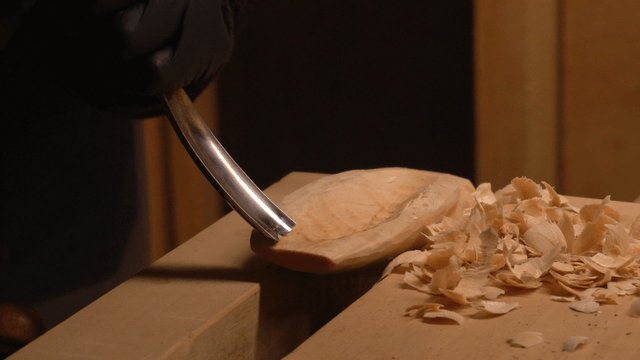 Woodcraft artisan carving a round groove in wood with a chisel