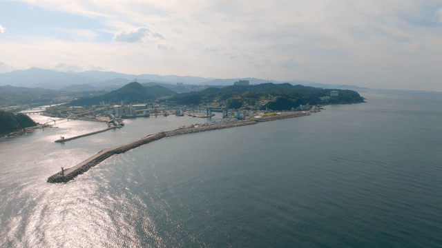 Wide sea in front of a coastal village beneath the mountain