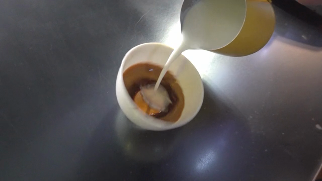 Pouring milk into a spinning coffee cup