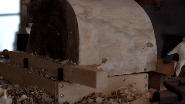 Woodcraft artisan inspecting round wooden piece in workshop